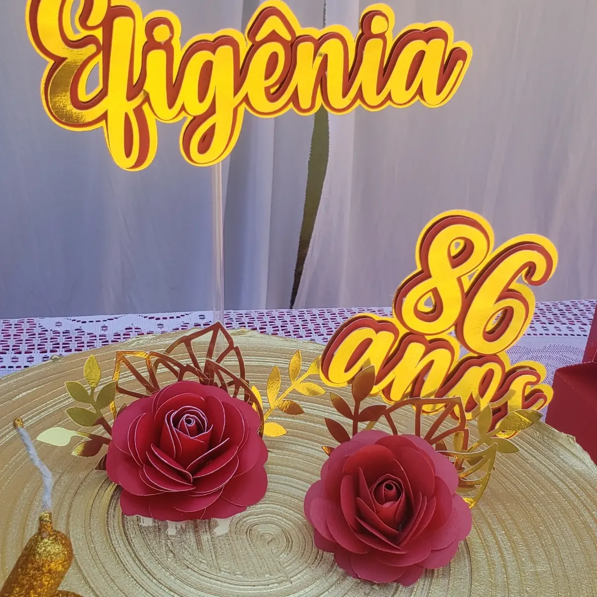 Topo com o nome Efigênia e 86 anos em amarelo e vermelho, com rosas de papel